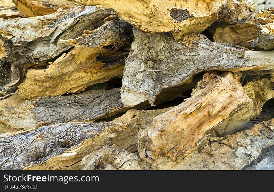 Background of dry roughly chopped firewood stacked up on top of each other in a pile