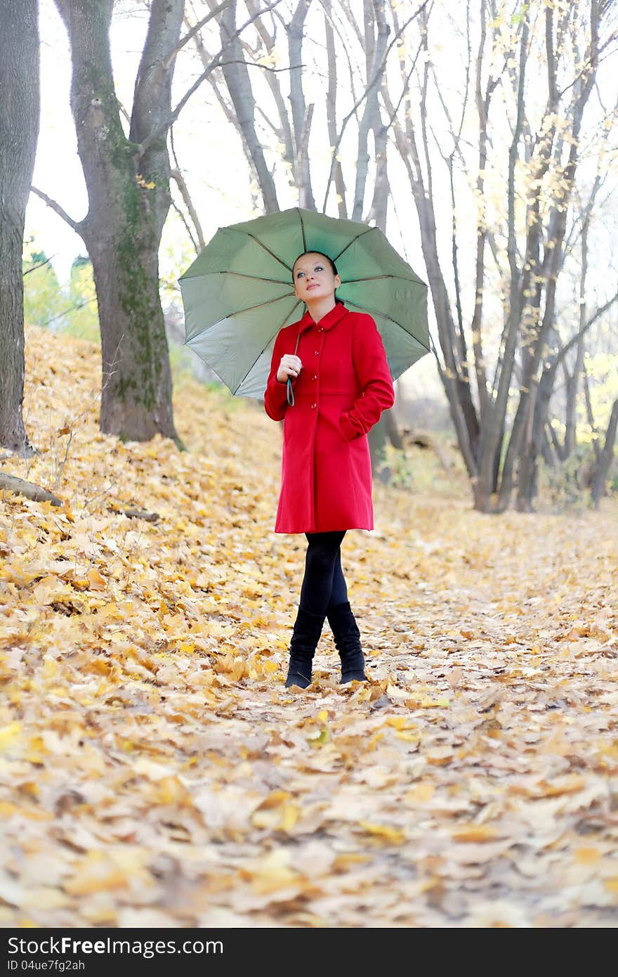 Pretty girl in the autumn forest with umbrella by day