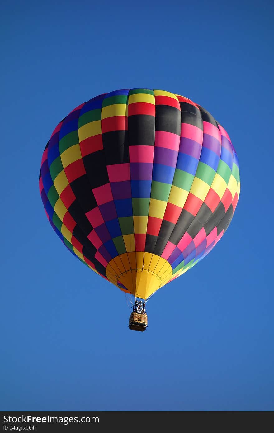 Checkered hot air balloon rising in blue sky