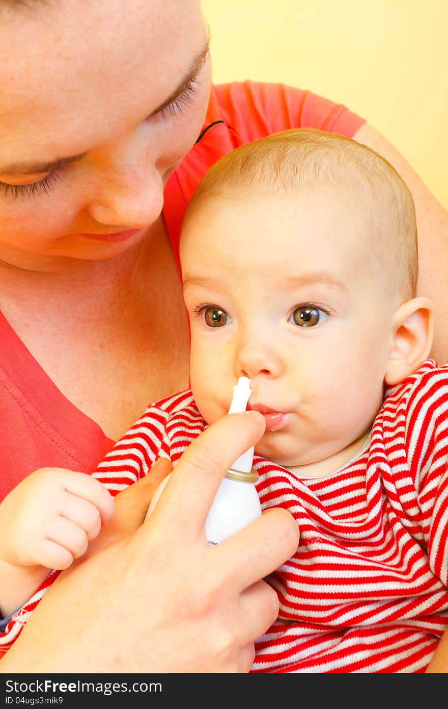 Mother using nose spray to cure her baby. Mother using nose spray to cure her baby.