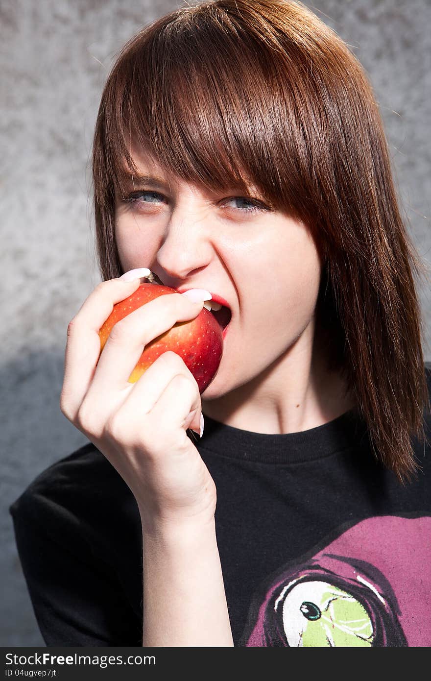 Young girl bites an red apple