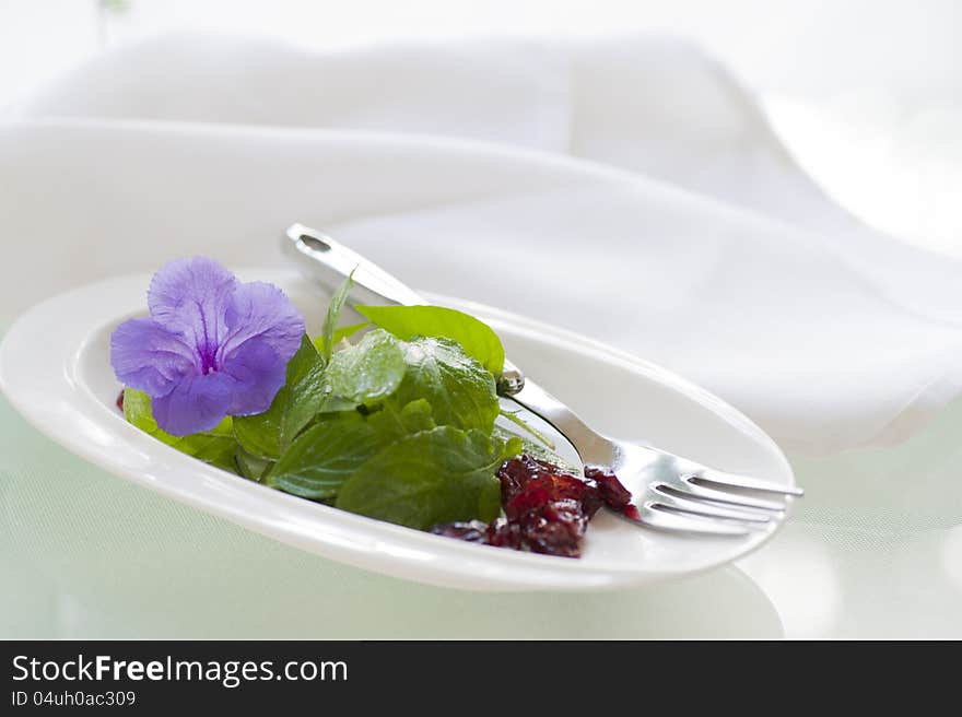 Delicious light salad of fresh greens and dried canberries garnished with an edible flower.