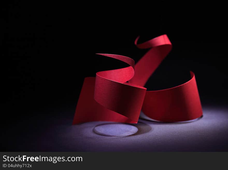 Abstract composition with red paper spiral on dark background. Abstract composition with red paper spiral on dark background