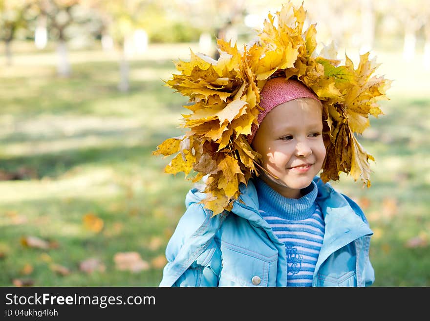 Small girl in a crown of autumn leaves