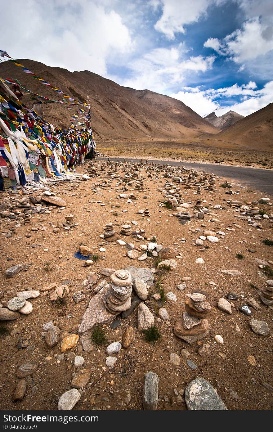 Highland road pass with stone pyramid and Buddhist praying flags. India, Ladakh, Leh-Chumathang-Tso Moriri highway, altitude 4500 m. Highland road pass with stone pyramid and Buddhist praying flags. India, Ladakh, Leh-Chumathang-Tso Moriri highway, altitude 4500 m