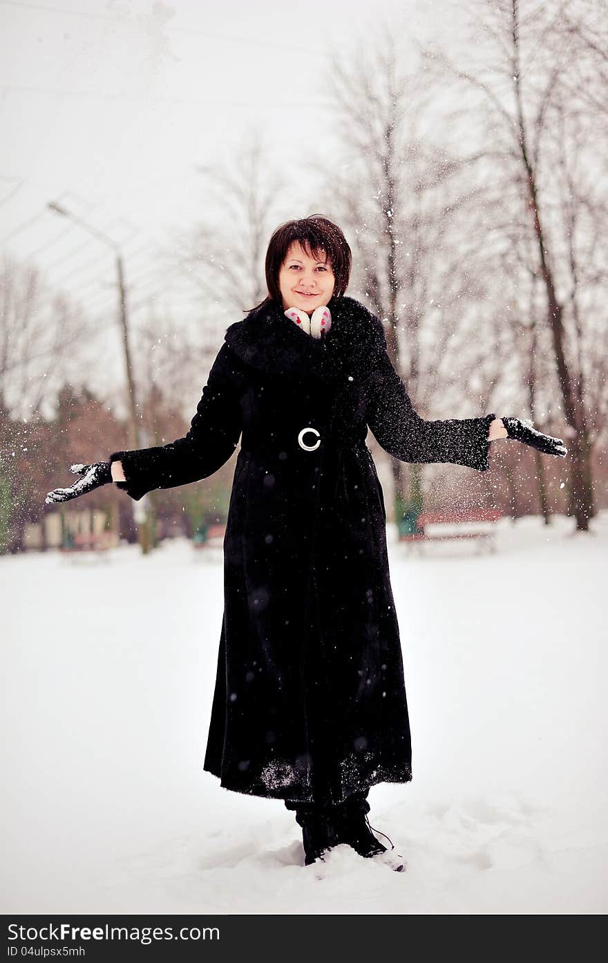 Outdoors in winter woman in a black fur coat playing with snow. Outdoors in winter woman in a black fur coat playing with snow