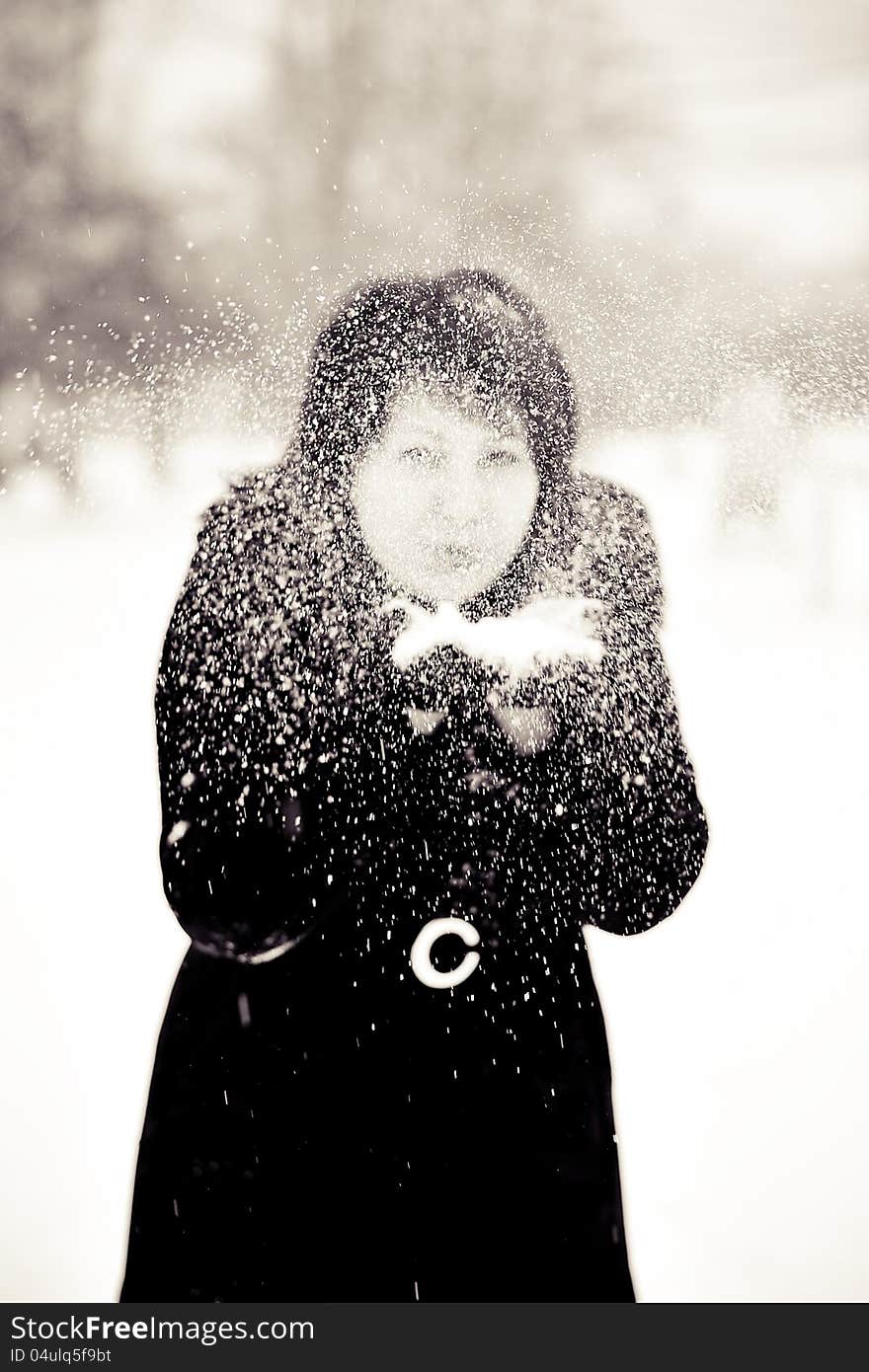 Outdoors in winter woman in a black fur coat playing with snow. Outdoors in winter woman in a black fur coat playing with snow