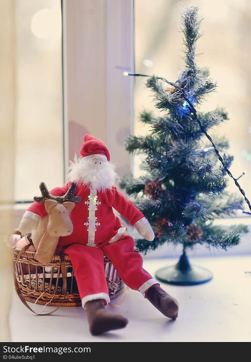 Christmas tree decorated with toys under the Christmas tree and Santa Claus with deer. Christmas tree decorated with toys under the Christmas tree and Santa Claus with deer