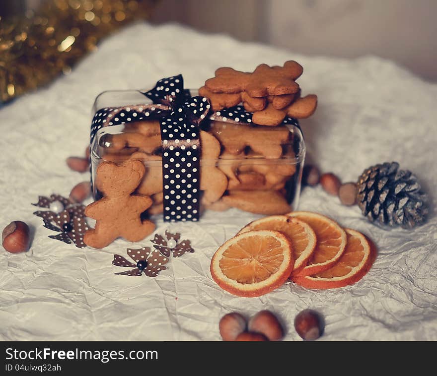 On a white table are dried orange segments and a box of biscuits, nuts and cones. On a white table are dried orange segments and a box of biscuits, nuts and cones