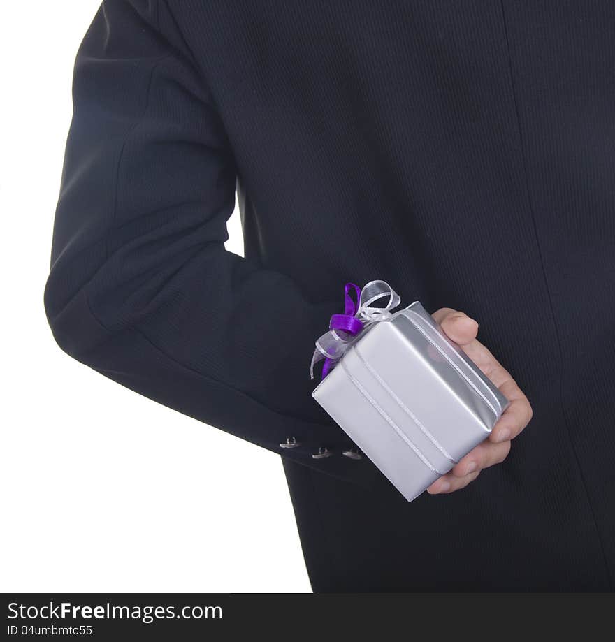 Man in a black suit hiding a present behind his back isolated on white background. Man in a black suit hiding a present behind his back isolated on white background