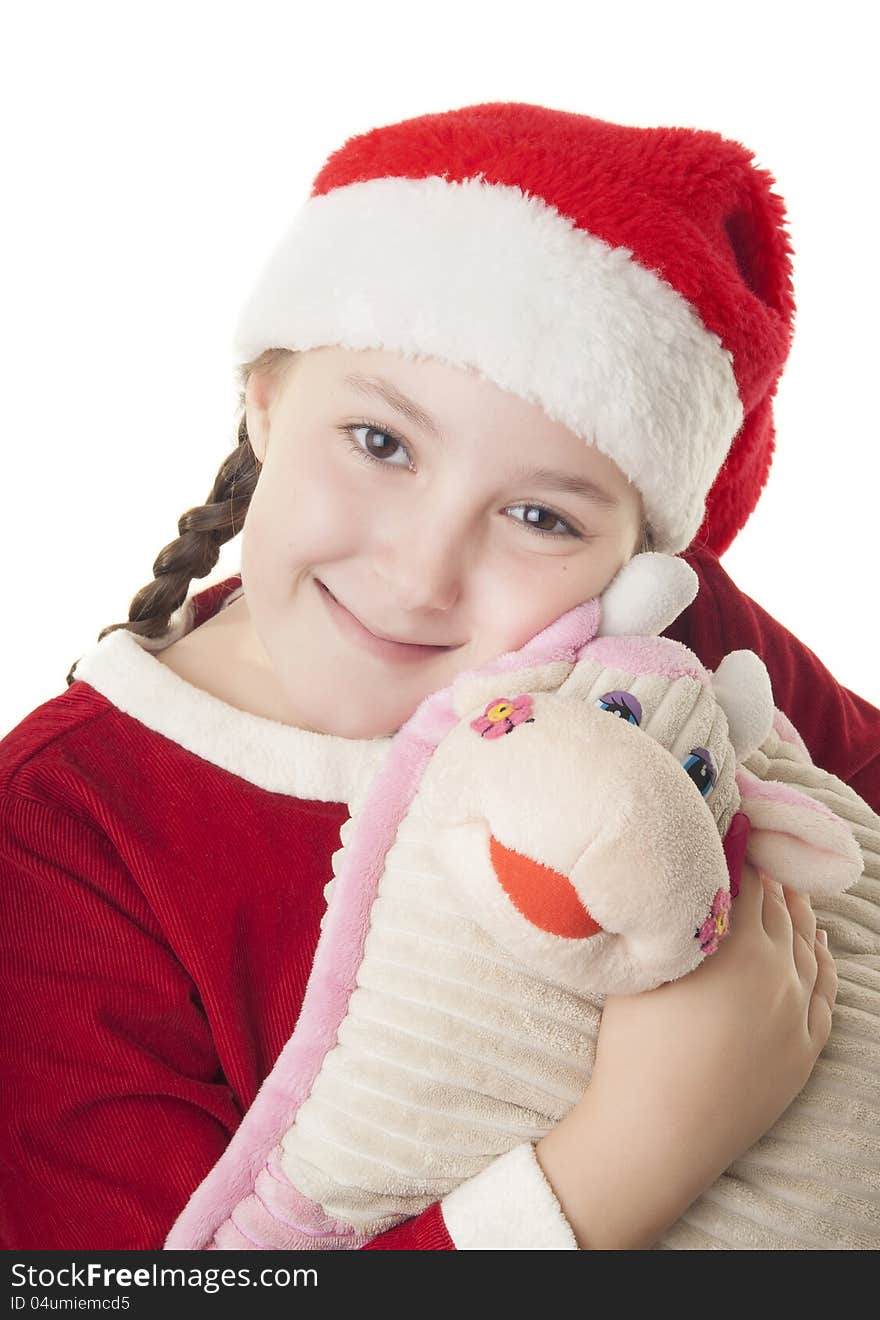 Beautiful girl dressed in Christmas clothes and red santa hat hugging cute cow pillow isolated on white background. Beautiful girl dressed in Christmas clothes and red santa hat hugging cute cow pillow isolated on white background