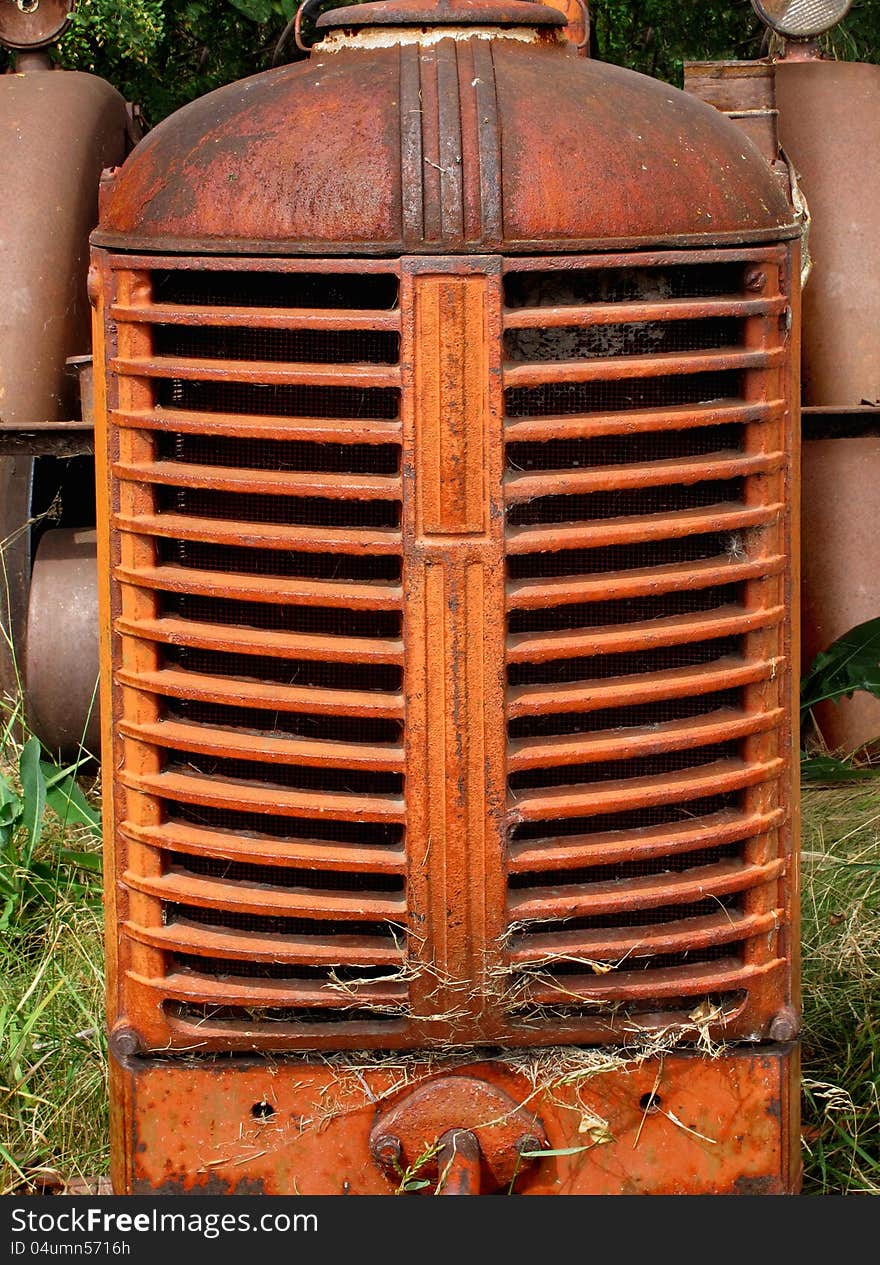 Close-up of a metal engine grill on an old orange abandoned farm tractor. Close-up of a metal engine grill on an old orange abandoned farm tractor.