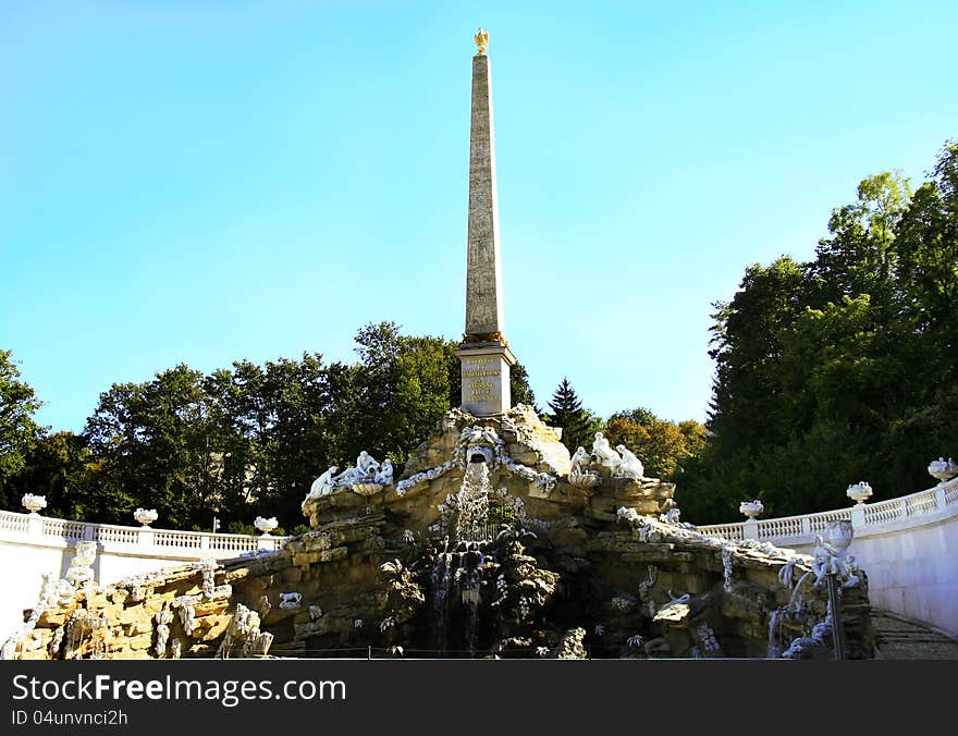 The grand obelisk fountain architectural ensemble in the gardens of Schonbrunn palace in Vienna Austria. The numerous statues decorating the central piece represent various allegories for Austrian rivers and nature. The main monolithic Egyptian obelisk rests atop the rock pedestal. The grand obelisk fountain architectural ensemble in the gardens of Schonbrunn palace in Vienna Austria. The numerous statues decorating the central piece represent various allegories for Austrian rivers and nature. The main monolithic Egyptian obelisk rests atop the rock pedestal.