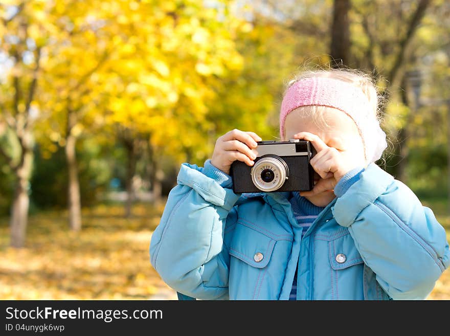 Small girl standing in autumn woodland taking a photograph using a vintage slr camera. Small girl standing in autumn woodland taking a photograph using a vintage slr camera