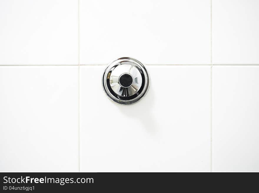 Chrome flush button on a white toilet against a white wall. Chrome flush button on a white toilet against a white wall.