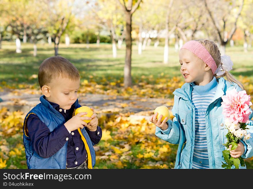 Little boy and girl eating apples while taking a walk together in a rural park
