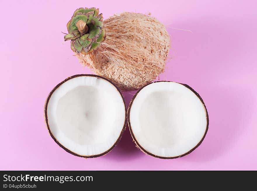 Two halfs of coconut  on pink background with shadow. Two halfs of coconut  on pink background with shadow