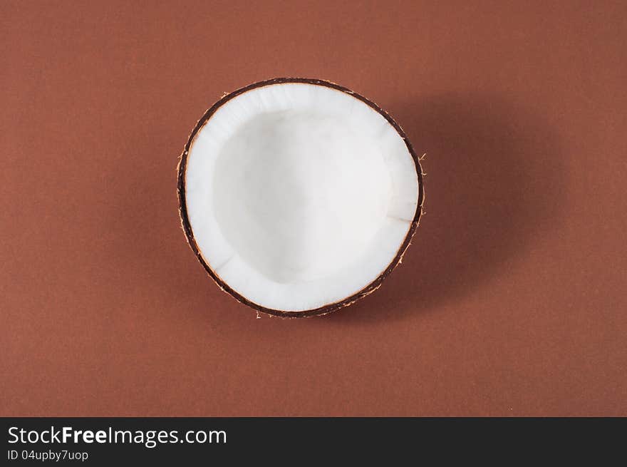 Halfs of coconut on brown background with shadow. Halfs of coconut on brown background with shadow