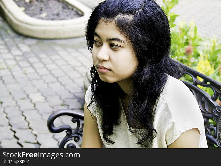 Sleepy girl sitting on a bench at park