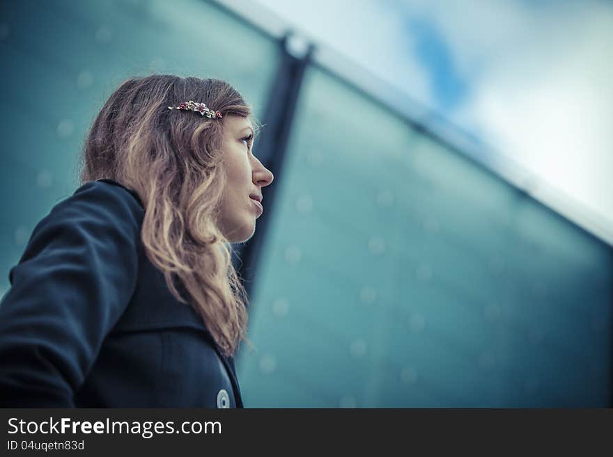 Girl looks on the sky with glass wall on background