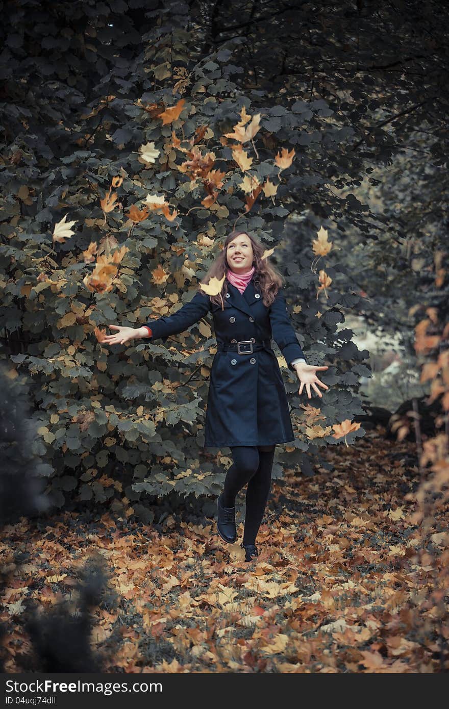 Girl plays with leaves falled from the trees