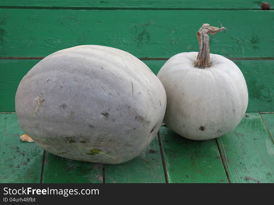 Two pumpkins on the green wooden table