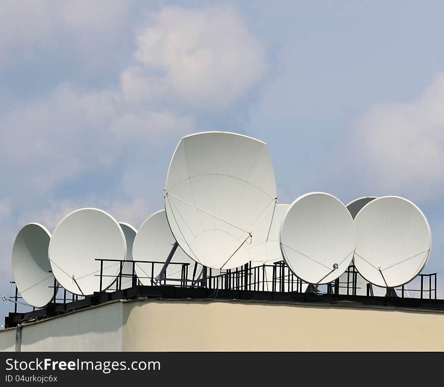 Many satellite dishes on the roof of a building