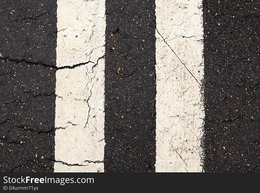 A close-up of white double-line markings on the road. A close-up of white double-line markings on the road