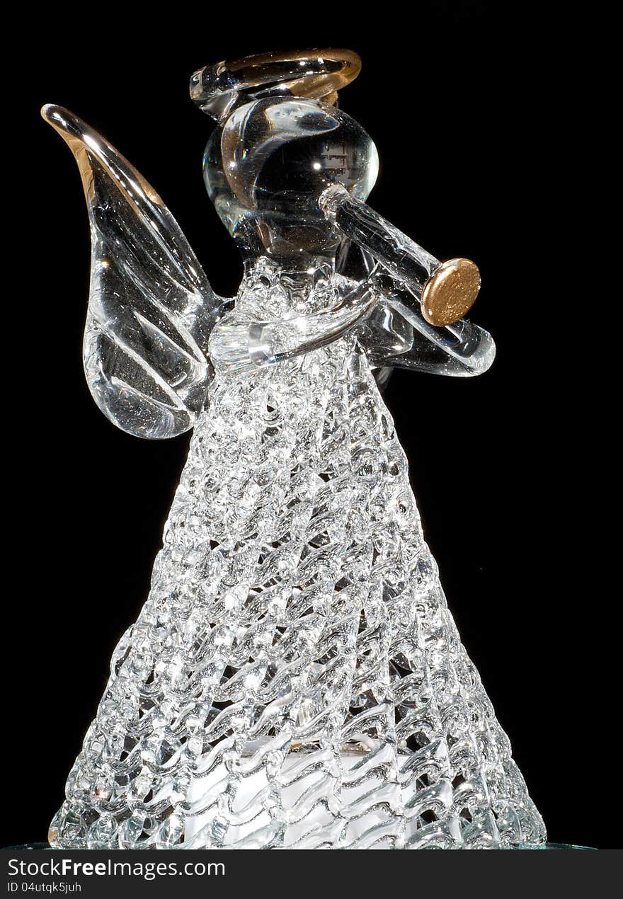 Ange-Statuette consisting of glass, playing a trumpet in front of black background. Ange-Statuette consisting of glass, playing a trumpet in front of black background