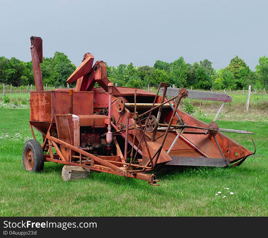 Old, weathered, and rusty farming combine to be pulled by a tractor. Against a pale blue sky for copy or text. Old, weathered, and rusty farming combine to be pulled by a tractor. Against a pale blue sky for copy or text.