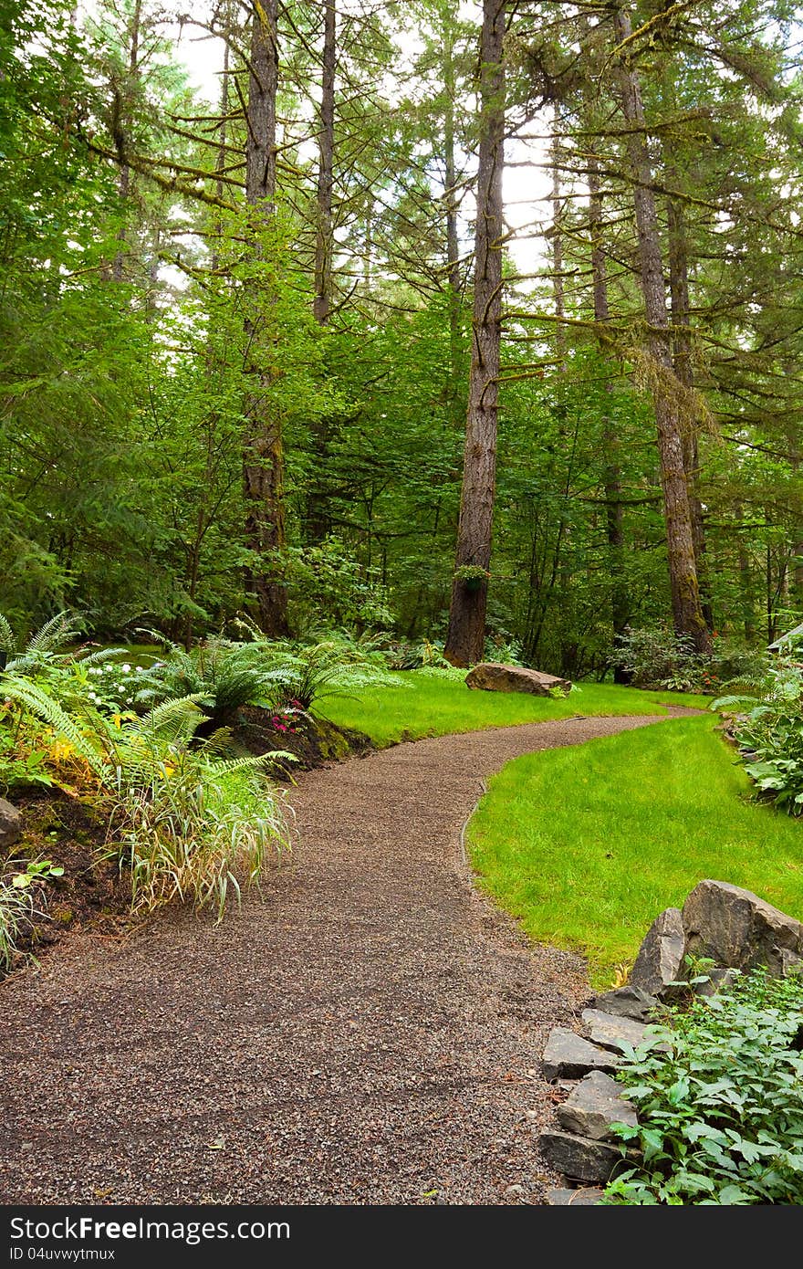 A beautiful path leads into a perfectly manicured garden at an Oregon wedding venue location. There is green, trees, plants, and stone in this vertical image. A beautiful path leads into a perfectly manicured garden at an Oregon wedding venue location. There is green, trees, plants, and stone in this vertical image.