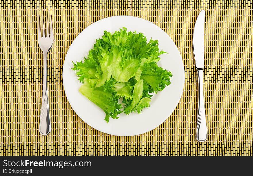 Diet concept. green leaf lettuce on a plate with a fork and knife. Diet concept. green leaf lettuce on a plate with a fork and knife