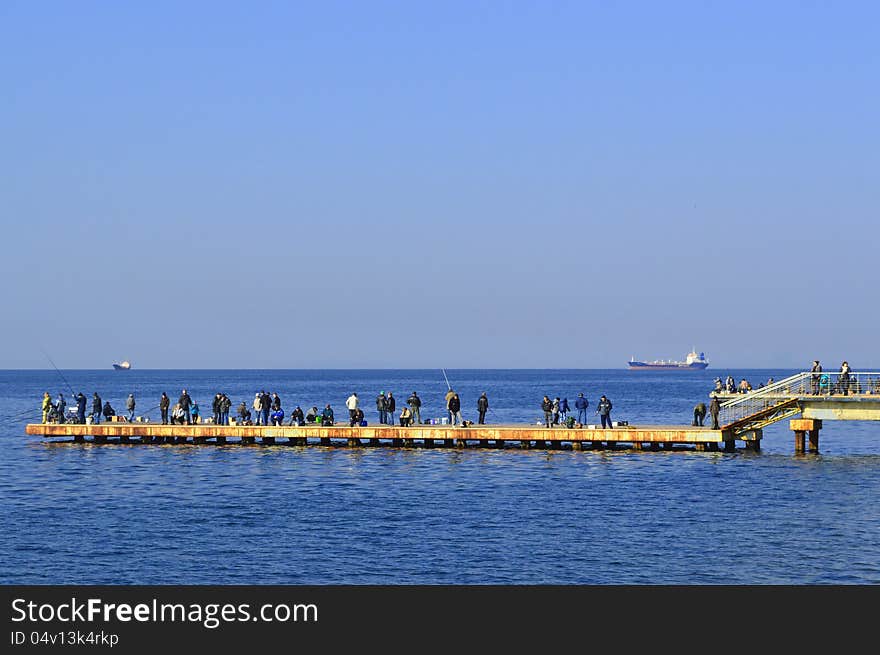 Fishermen on the berth on the sea background