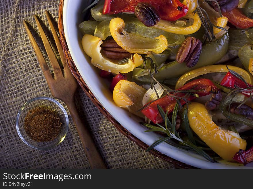 Dish of roasted paprika with pecan and rosemary. A rustic still life.