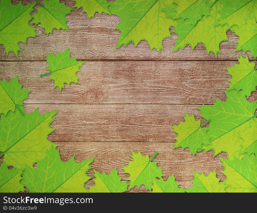 Green maple leaves over wooden background