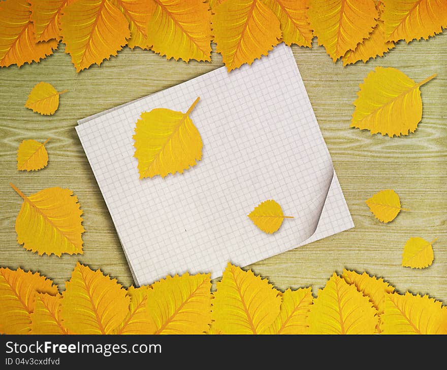 Yellow leaves over wooden background