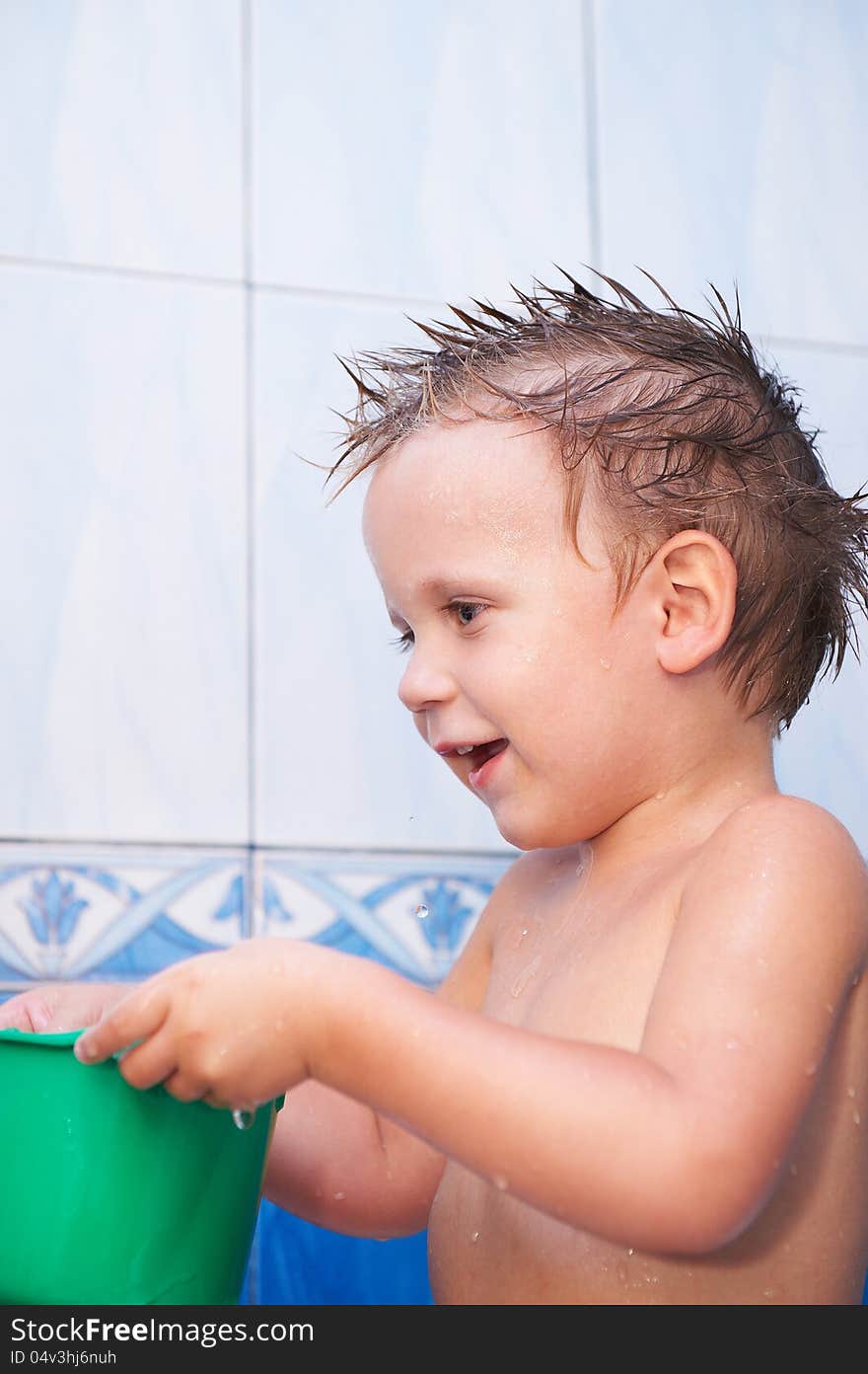 Happy baby in bath with green bucket