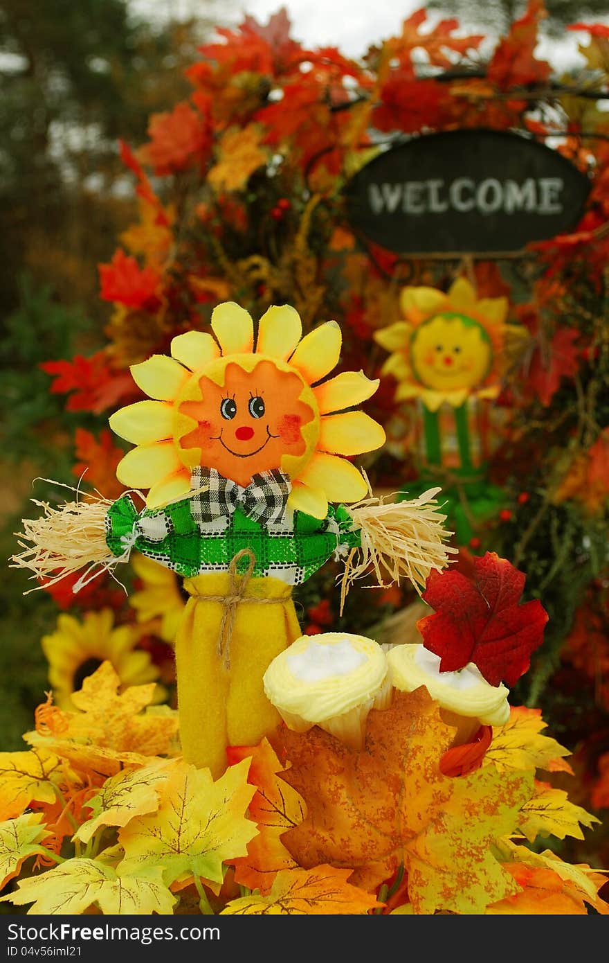 Thanksgiving or festive autumn display with a scarecrow, cupcakes, and a welcome sign in the background. Thanksgiving or festive autumn display with a scarecrow, cupcakes, and a welcome sign in the background.