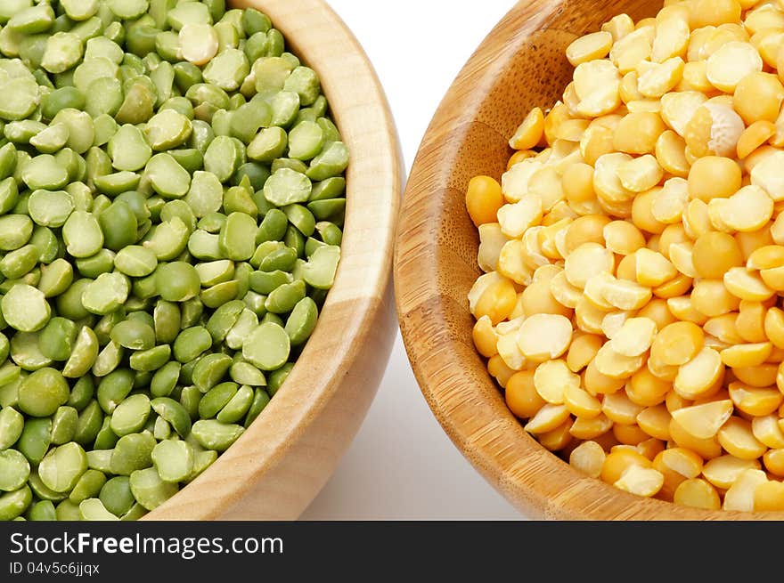 Green and Yellow Split Peas in Wooden Bowls closeup on white background. Green and Yellow Split Peas in Wooden Bowls closeup on white background