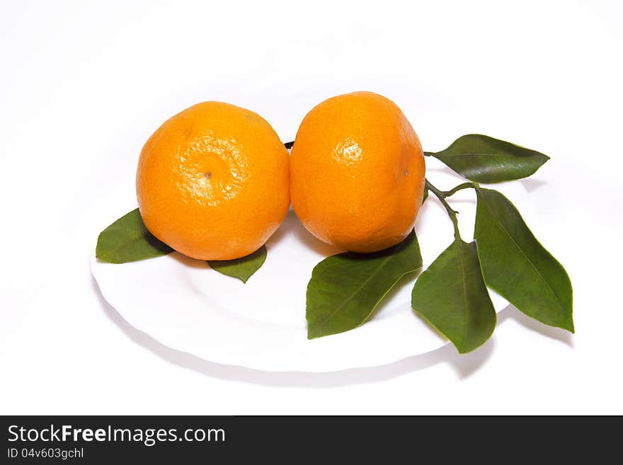 Two tangerines wiht leaves on white plate, isolated on white background