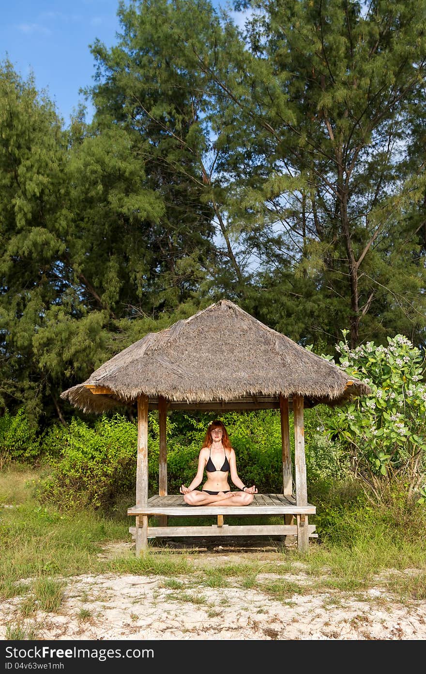 Young woman doing yoga lotus meditation in pavilion near ocean. Young woman doing yoga lotus meditation in pavilion near ocean