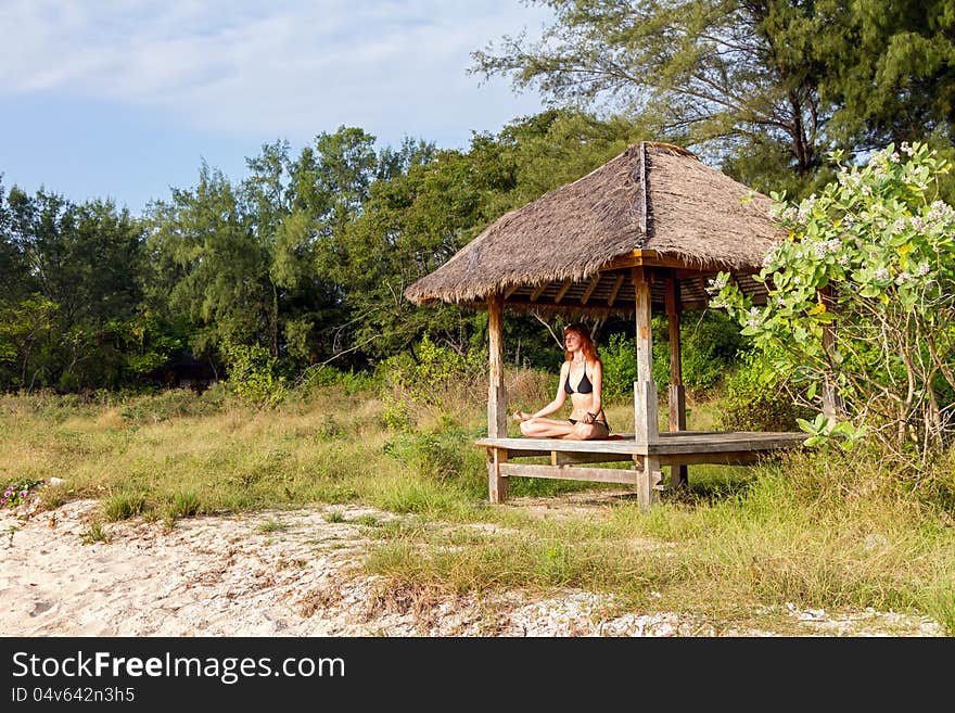 Woman Doing Yoga Meditation In Tropical Gazebo