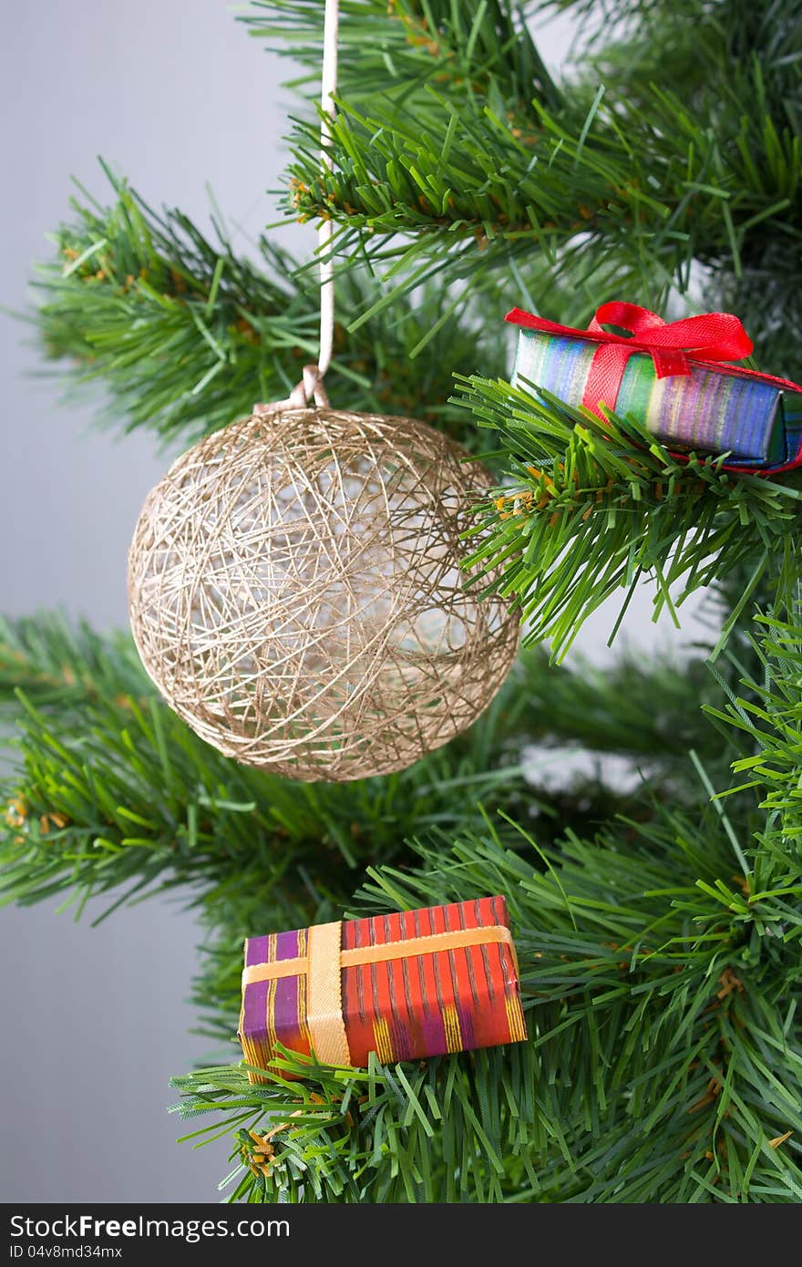 Christmas golden ball on the tree with packed gift