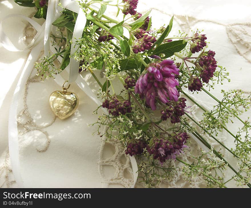 Alpine flowers on a pillow with golden heart in a sunny window. Alpine flowers on a pillow with golden heart in a sunny window.