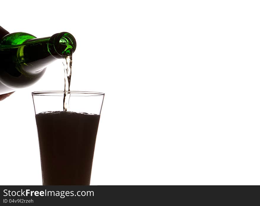 Beer pouring from green bottle into glass  on white