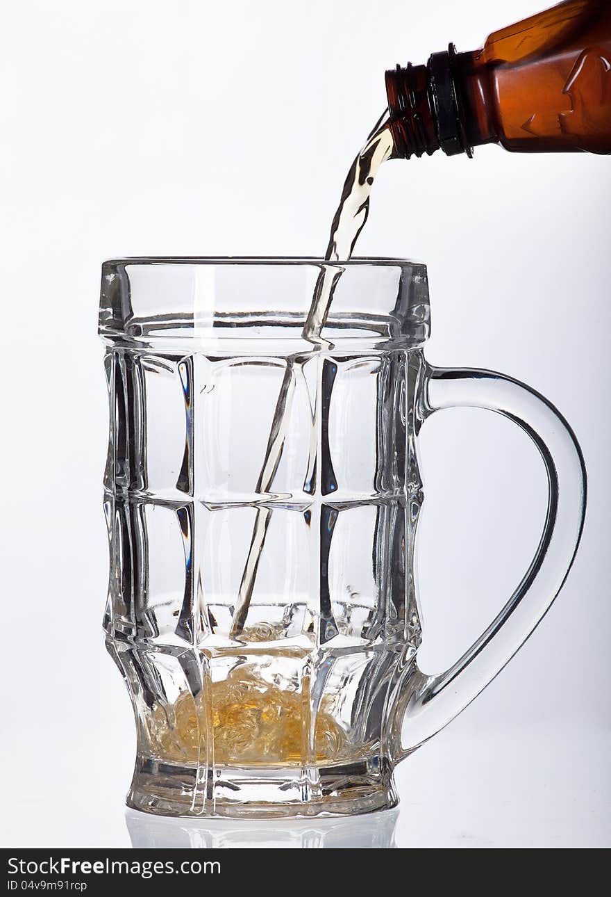 Beer pouring into beer mug isolated on white