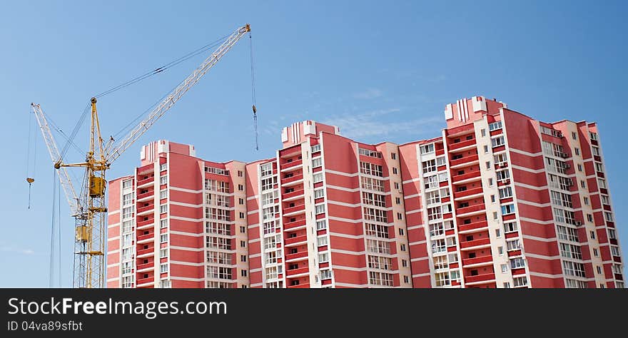 The elevating crane against the dark blue sky, building a monolithic building.