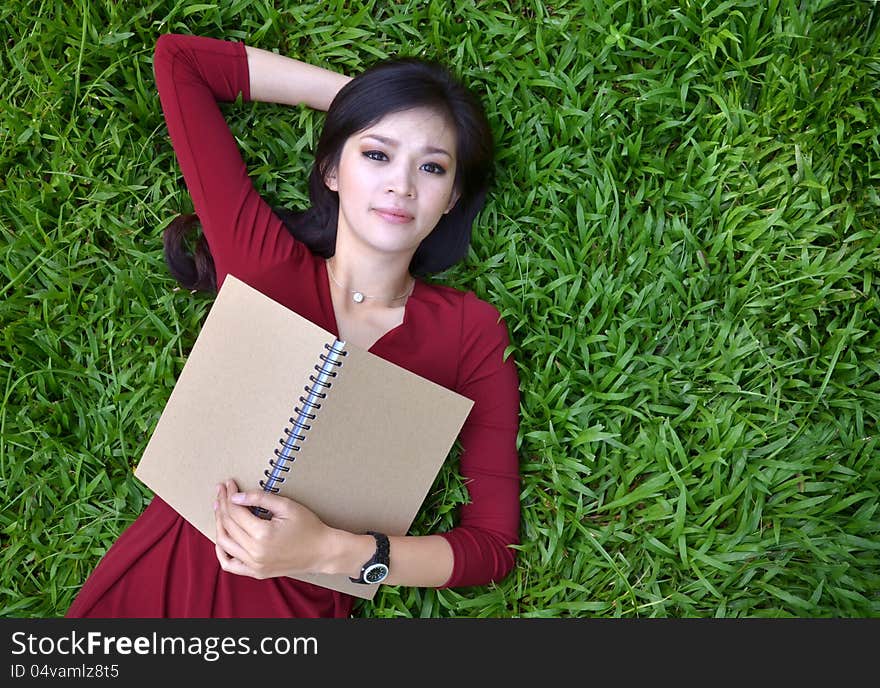 Woman lying on grass with book