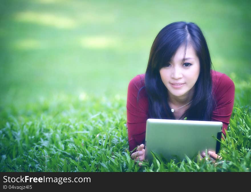 Pretty woman using tablet outdoor laying on grass