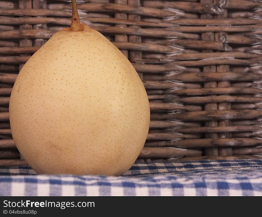 Asian Pear on a blue checked table cloth stood by a willow weave picnic basket. Asian Pear on a blue checked table cloth stood by a willow weave picnic basket